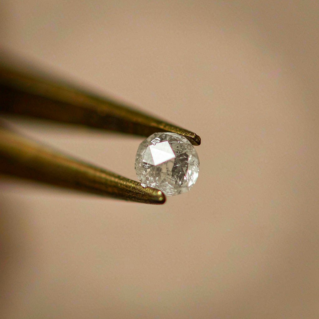 Close-up of a steel tweezer holding an unset round diamond