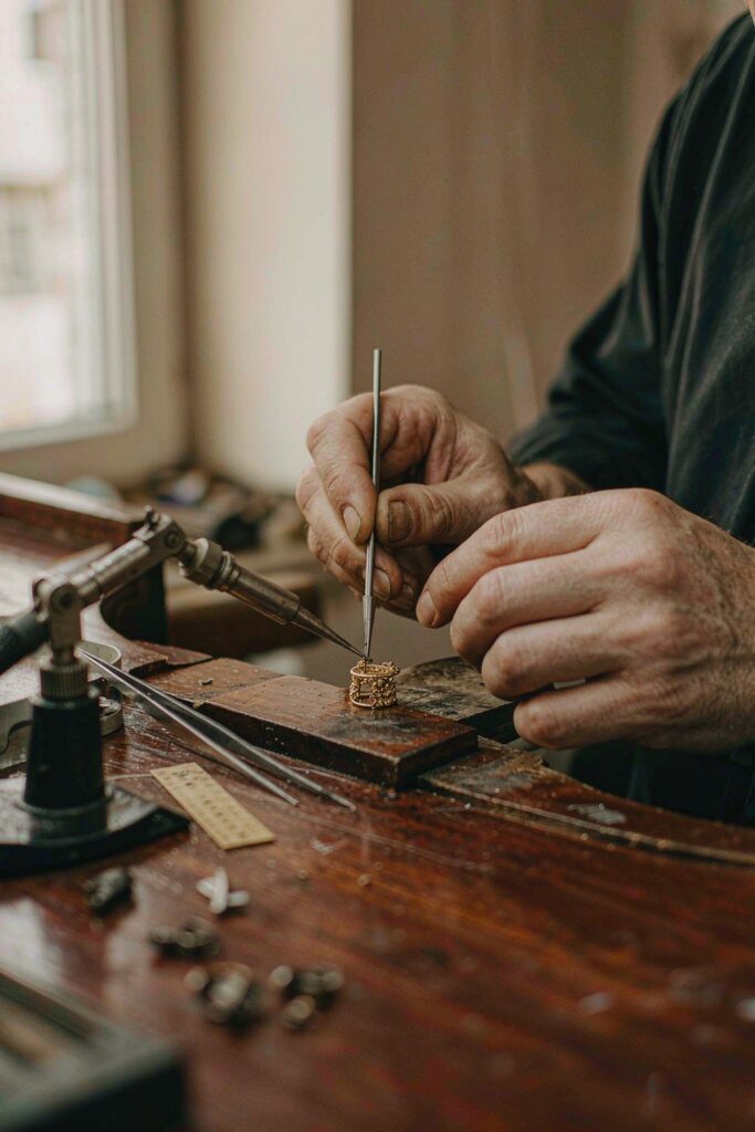 A jeweller working at a bench, shaping a gold ring by hand